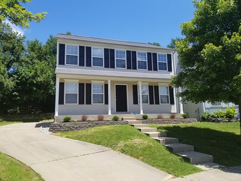 a white house with black shutters and a sidewalk in front of it